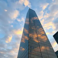 FLUX.1 [schnell] — A modern glass skyscraper reflecting clouds at sun