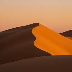 Imagen 3 — A desert sand dune at sunset with long shadows, Sa