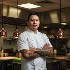 Imagen 3 — A tattooed chef in a white coat, arms crossed, con