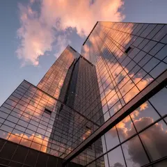 Imagen 4 Fast — A modern glass skyscraper reflecting clouds at sun