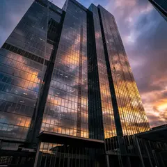 Imagen 4 Ultra — A modern glass skyscraper reflecting clouds at sun