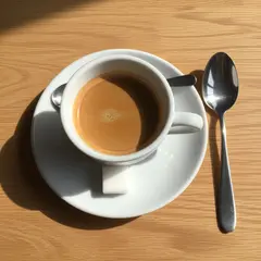 Imagen 4 — A cup of coffee on a saucer, with a spoon to the r