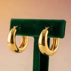 Imagen 4 — A pair of gold hoop earrings on a velvet jewelry d