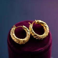 Luma Photon — A pair of gold hoop earrings on a velvet jewelry d