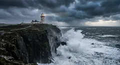 Gemini 3.1 Flash Image — A coastal cliff with crashing waves below, lightho