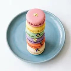 Qwen Image 2.0 — A stack of colorful macarons on a pastel blue plat