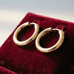 Qwen Image 2.0 — A pair of gold hoop earrings on a velvet jewelry d