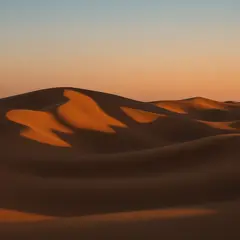 Qwen Image — A desert sand dune at sunset with long shadows, Sa