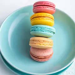 Recraft V3 — A stack of colorful macarons on a pastel blue plat