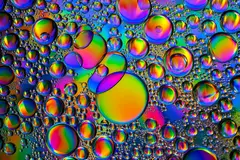 Reve v1.0 — A macro photograph of oil droplets on water, iride