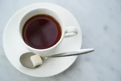 Reve v1.0 — A cup of coffee on a saucer, with a spoon to the r