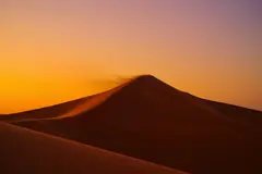 Reve v1.0 — A desert sand dune at sunset with long shadows, Sa