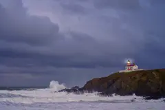 Reve v1.0 — A coastal cliff with crashing waves below, lightho