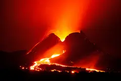 Reve v1.0 — A volcano erupting at night with lava flowing down