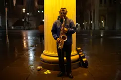 Reve v1.0 — A street musician playing saxophone under a lamppo