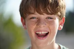 Reve v1.0 — A freckled boy with bright blue eyes and messy hai