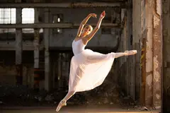 Reve v1.0 — A ballet dancer mid-leap in an abandoned warehouse