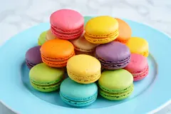 Reve v1.0 — A stack of colorful macarons on a pastel blue plat