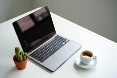 Reve v1.0 — A sleek laptop on a clean white desk with a potted