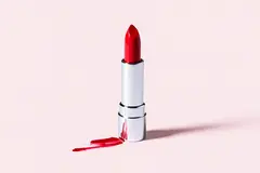 Reve v1.0 — A tube of red lipstick standing upright, melting s