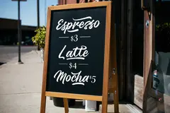 Reve v1.0 — A hand-lettered chalkboard menu outside a coffee s