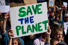 Reve v1.0 — A protest sign held up in a crowd reading SAVE THE