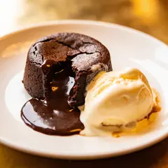 Seedream v4.5 — A dripping chocolate lava cake cut open on a white