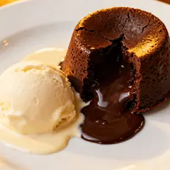 Seedream v4 — A dripping chocolate lava cake cut open on a white