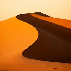 Seedream v4 — A desert sand dune at sunset with long shadows, Sa