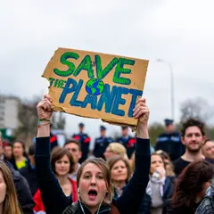 Wan 2.6 T2I — A protest sign held up in a crowd reading SAVE THE